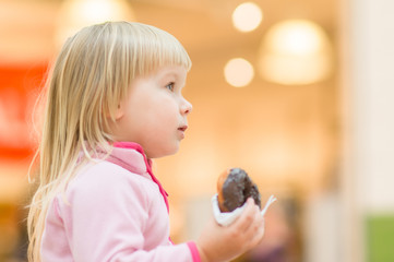 Adorable baby eat donut with chocolate holding it with napkin in