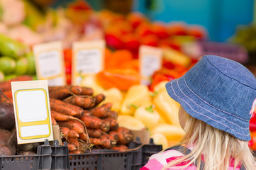 Adorble girl near bunch of fruits and vegetables in city market