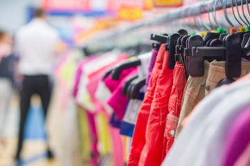 Bright trousers and t-shirts on stands in supermarket