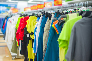 Fototapeta premium Color T-shirts and sport trousers on stands in supermarket