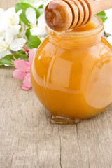 Fototapeta na wymiar honey in glass jar and stick with flowers
