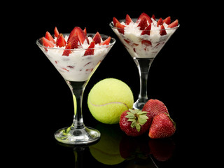 Tennis sphere and wild strawberry with cream in two glasses with