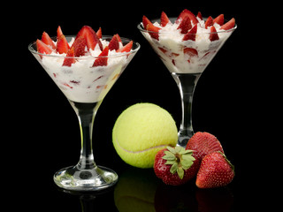 Tennis ball and strawberry with cream in two glasses.