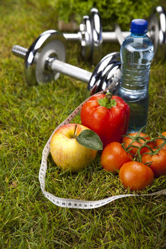Vitamin and Fitness diet, dumbell in green grass 