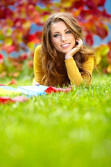 Portrait of a gorgeous brunette woman reading a book in the autu