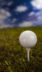 Golf ball on green grass over a blue sky 