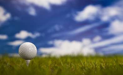 Golf ball on green grass over a blue sky 