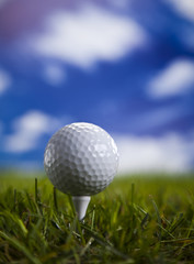 Golf ball on green grass over a blue sky 