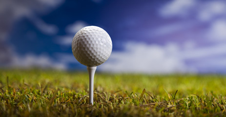 Golf ball on green grass over a blue sky 