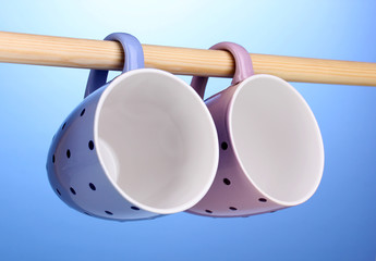 Nice cups hanging on stick on blue background
