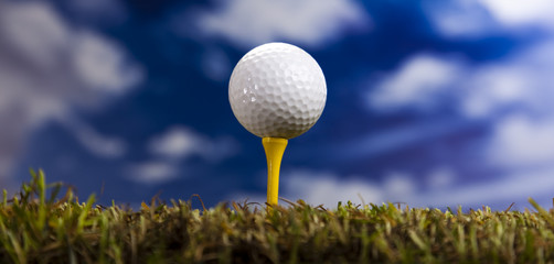 Golf ball on green grass over a blue sky 