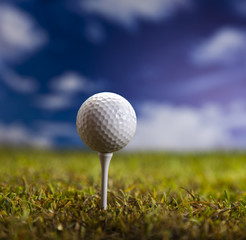 Golf ball on green grass over a blue sky 