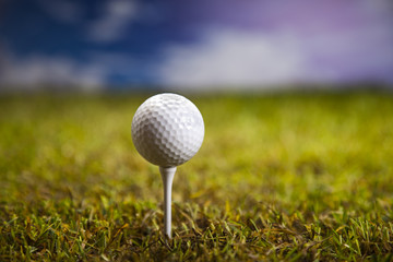 Golf ball on green grass over a blue sky 