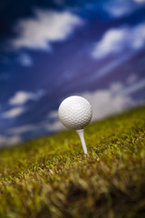 Golf ball on green grass over a blue sky 