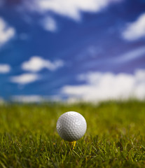 Golf ball on green grass over a blue sky 