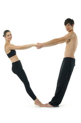 Couple gymnasts practicing a complex double yoga pose.