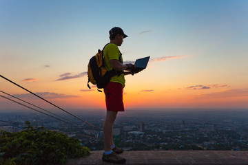 young man with a laptop at sunset.
