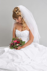 Beautiful bride with stylish make-up and hairdo holding bouquet
