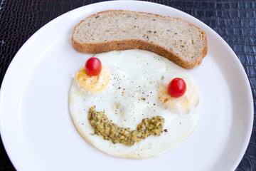 Smiley face from fried eggs with cherry tomatoes