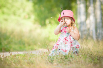 Adorable girl in red hat play with branches in park