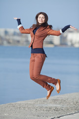 Young businesswoman jumping on seafront