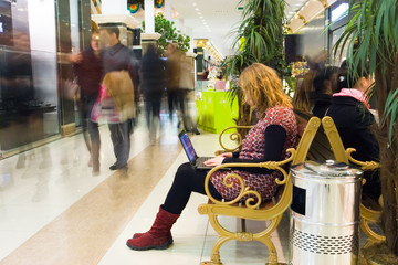 Woman working on laptop in the mall