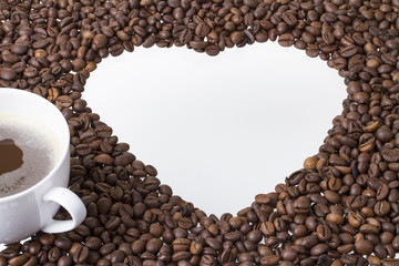 neben herz aus kaffeebohnen steht eine tasse kaffee