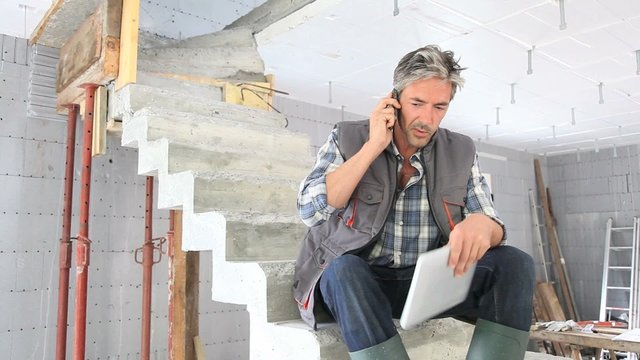 Construction manager using mobile phone on building site