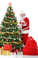 Santa beside Christmas tree with gift