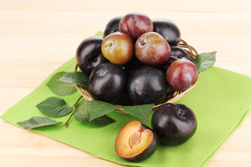 Rip plums on basket on wooden table