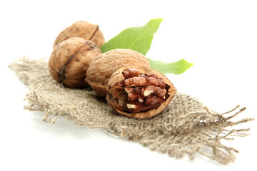 walnuts with green leaves on burlap, isolated on white