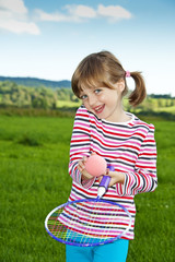 little girl playing children tennis on a meadow