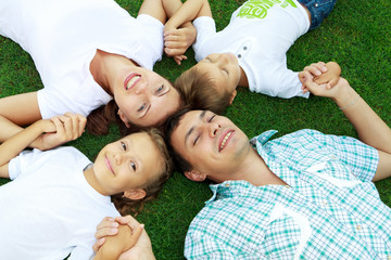 Семья с двумя детьми лежит на траве, вид сверху