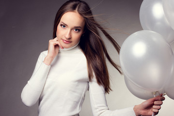 Beautiful fashion woman in studio with white balloons