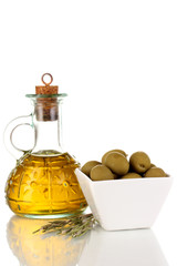 Green olives in white bowl with rosemary and olive oil isolated