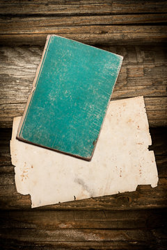 Dark faded book and crumpled paper on wood