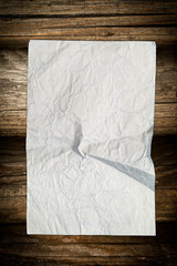 Aged crumpled paper sheet on wood