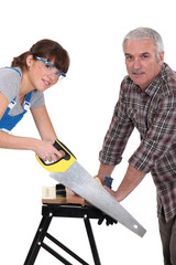 Father and daughter sawing plank of wood