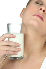Woman putting a glass of cold milk against her neck