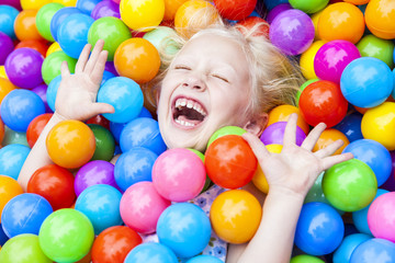 Fototapeta na wymiar Blond dziecko dziewczyna zabawy Gra w Kolorowe Kulki