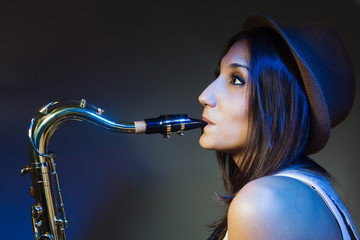 Obraz na płótnie Canvas joven y atractiva mujer con gorro tocando el saxofon