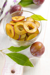 Fresh wet plums with leaves in the bowl on the vintage board