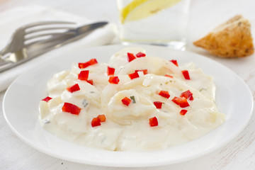 potato salad with pepper and sauce on the white plate