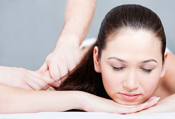 Woman receives body massage at beauty salon