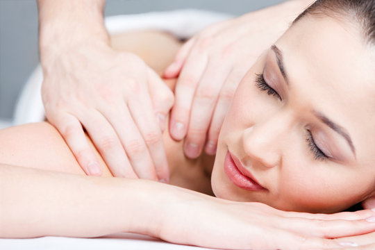 Woman receives body massage at spa salon