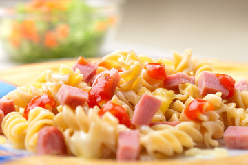 Curly pasta with slices of ham and tomato sauce