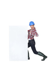 A female construction worker by a billboard.