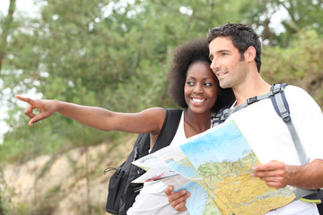 Couple reading map outdoors - Powered by Adobe