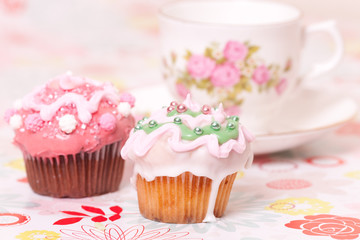 two pink cup cakes and tea cup