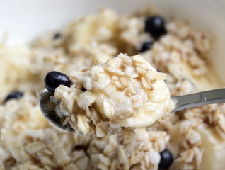 spoon of oatmeal porridge with bilberries and bananas